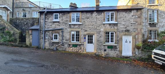 Front door with small step and car parking outside cottage