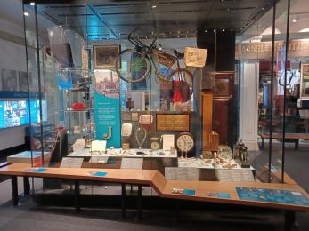 Museum display case featuring objects such as a bike and a clock