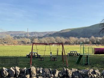 Play equipment in a field with swings and view over the Peak District