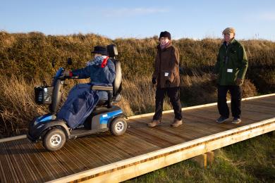 Mobility scooter user and two visitors using the boardwalk 
