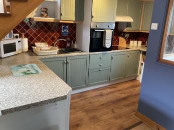 Kitchen in Albany Cottage showing cupboards, standard height work surfaces and wooden floor with clear circulation space.
