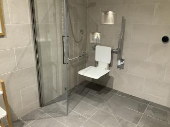 Spacious wet room with folding shower screen and shower chair