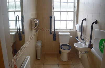 Image of the accessible toilet room. Includes mirror, hand dryer, handrails, toilet, low sink and baby changing facilities. 