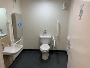 Accessible toilet with hand rails and additional space for wheelchair users.