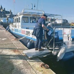 Assisting Wheelchair Passenger onto boat, using the ramp at stern of boat.  