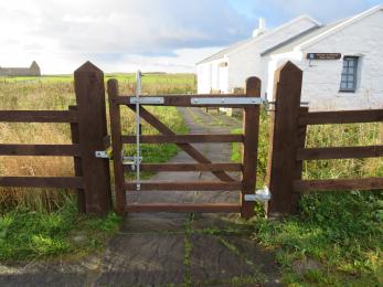 A wide wooden gate with a two-way opening hinge is the opening between the parking area and the visitor centre. 
