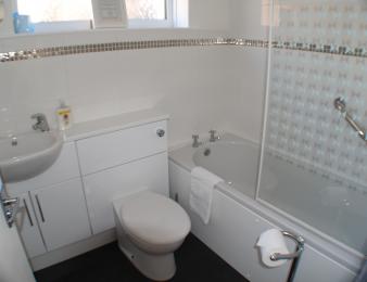 Bathroom with sink, toilet and bath. Toilet with right transfer direction