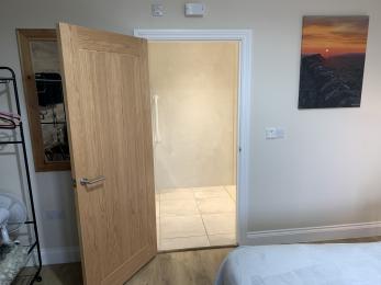 Accessible room showing space by bed and entrance to accessible shower room