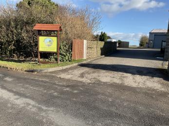 Entrance to Summerfield Farm showing wide entrance driveway and Summerfield Farm sign to the right.