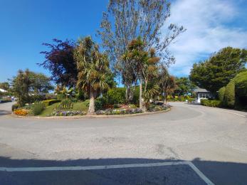 Entrance roundabout with palm trees and flowers, and a wide tarmac road with easy access to the reception building and main park
