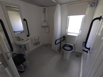 Accessible wetroom in our Kynance caravan with raised toilet, shower, shower seat, accessible sink, level access, sliding door.