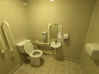 Disabled toilet with handrails, accessible sink, adjusted toilet, and emergency alarm.