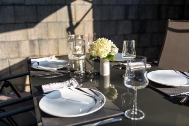 The patio dining table is a smoked glass colour, providing contrast with plates.