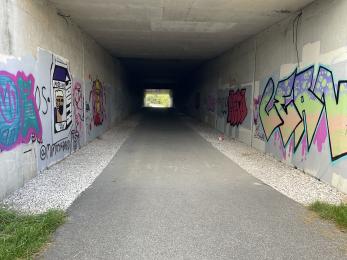 Underpass tunnel part way along the trail with graffiti on the walls to the left and right.