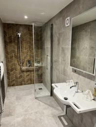 Wetroom showing the folding shower screen and wheelchair accessible basin