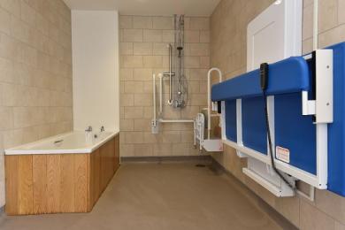 Accessible wet room with rise and fall adult changing bed, shower, toilet and a bath (bath not accessible)
