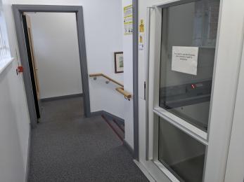 The lift on the first floor, near the stairs and door to the Community Room.