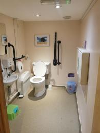 Image of the inside of the accessible toilet, showing grab rails, sink, WC and baby changing facilities 