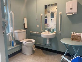 vistors toilet with handrails beside toilet and sink. 