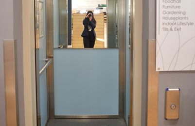 Image of customer lift with doors open. Showing mirror at back of the lift and handrail inside the lift.