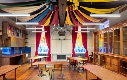 Magic Common Room interior with tables and ribboned ceiling