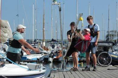 Hoisting a person into the sailing boat on the pontoon at Mylor Sailing and Powerboat School Falmouth Cornwall