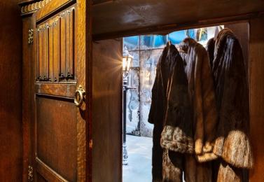 The view through open cupboard doors of hanging fur coats and Narnia