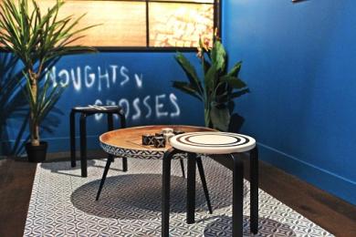 The table and stool inside the blue Noughts and Crosses room