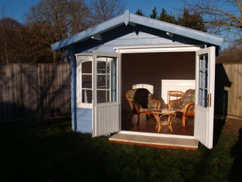 A summerhouse with the double doors open in evening sunshine with a step up and a door threshold