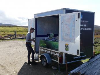 A person stands in front of a display trailer which stands approximately 2.4m high. There are two steps to access the trailer. 
