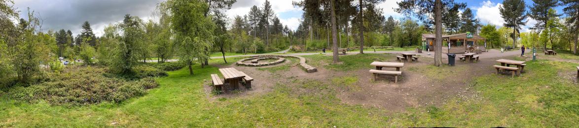 Panoramic image of picnic tables and hardcore path leading onto trail.