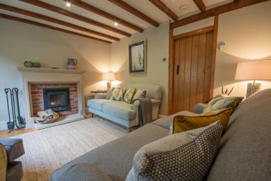 Sitting room with a three seater, large two seater, occasional chair and log burning stove.