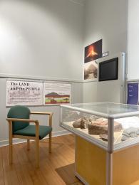 Museum Room 2 showing audio visual area, lower placed interpretation panels, display case and seating.