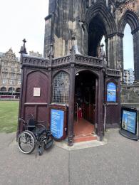 A wheelchair next to the entrance and ticket counter for the Scott Monument