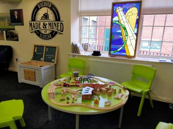 Children's craft area with green tables and chairs and a model train set