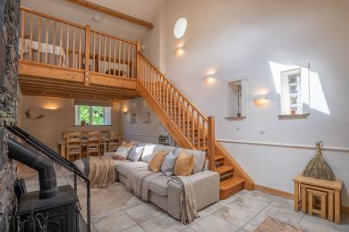The byre living area showing sofa and stairs to mezzanine