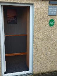 Image shows guest entrance with door open.  Burnside Cottage B&B sign & Green Tourism Gold award visible