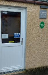 Image shows guest entrance with door closed. Burnside Cottage B&B sign and Green Tourism Gold award visible