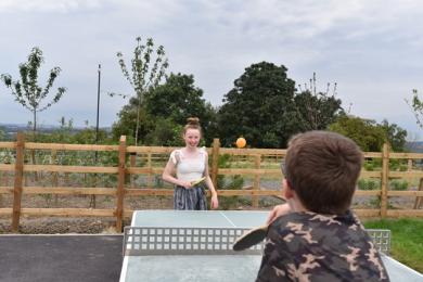 Outdoor table tennis on level ground near reception and coffee shop bar area