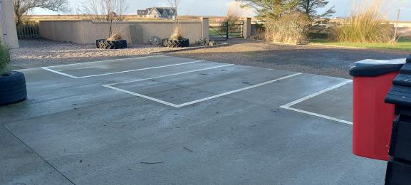 Image is of the view directly out from the guest entrance to the car park with the graveled area and lawned areas beyond