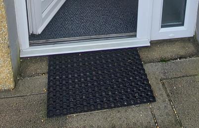 Image is of the exterior rubber door mat and threshold ramp leading into The Pig Shed hallway