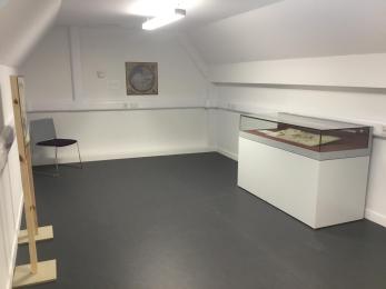 Image shows Research Studio layout. To the right, there is a low glass cabinet with an object on display. 
