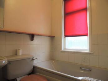 bathroom with bath, toilet cistern and red blind in view