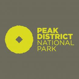 National Park logo with yellow writing on a grey background with a yellow image of a millstone.