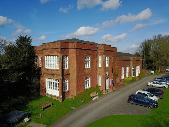 A picture of Saffron Walden Museum, showing a large red brick building, with cars in the car park