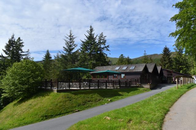 A forest visitor centre with trees and mountains behind