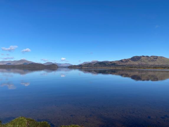 View over loch towards conic hill with blue sky. 