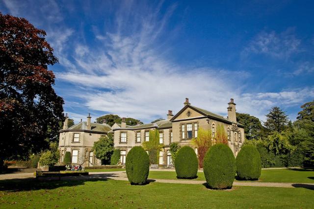 Photograph of the exterior of Lotherton Hall. A large house with green gardens in front.